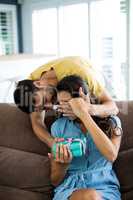 Young man giving a surprise gift to woman in the living room