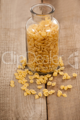 Conchiglie pasta spilled out of glass jar