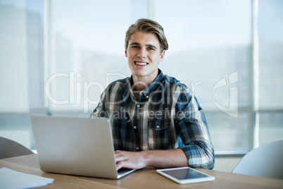 Smiling man working on laptop in office