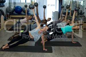 Fit women performing stretching exercise with fitness ball in gym
