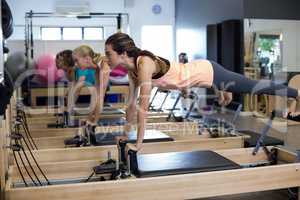 Determined women practicing stretching exercise on reformer