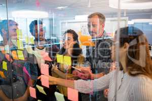 Creative business team looking at sticky notes on glass window