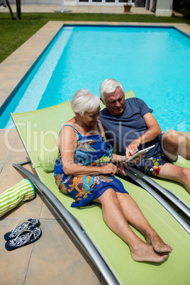 Senior couple using digital tablet on lounge chair