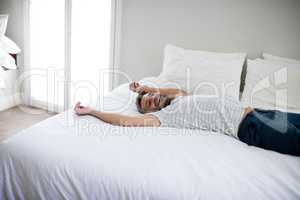 Man lying on bed with arms up on bed