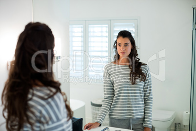 Woman looking at herself in the bathroom mirror