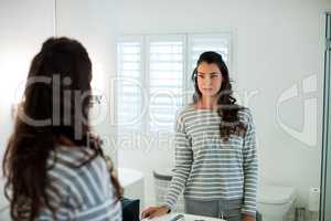 Woman looking at herself in the bathroom mirror