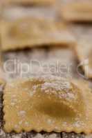 Ravioli pasta dusted with floor on wooden background
