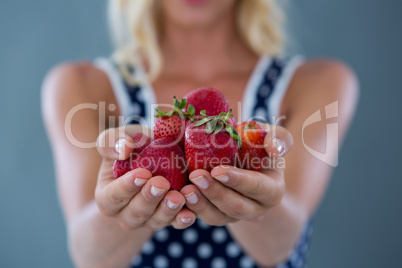 Mid-section of woman holding strawberries