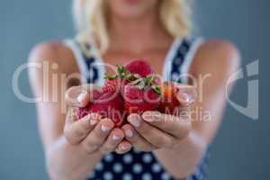 Mid-section of woman holding strawberries