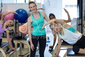 Smiling female trainer assisting woman with exercise