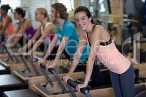 Portrait of smiling woman exercising on reformer