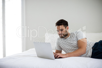 Man using laptop on bed