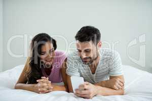Couple using mobile phone in the bedroom