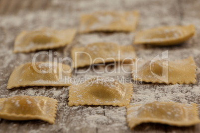 Ravioli pasta dusted with floor on wooden background