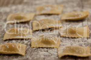Ravioli pasta dusted with floor on wooden background