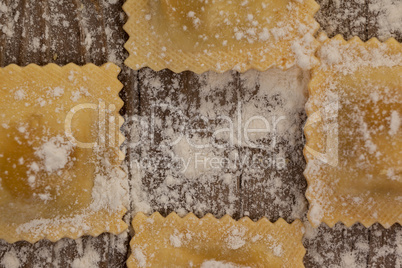 Ravioli pasta dusted with floor on wooden background