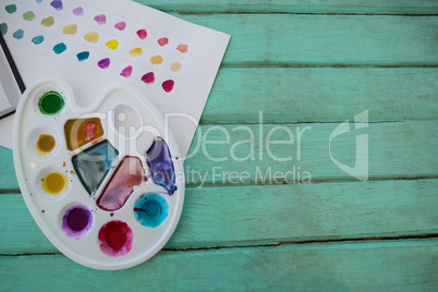 Colorful palette and paper on wooden surface