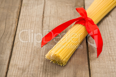 Bundle of raw spaghetti tied with red ribbon