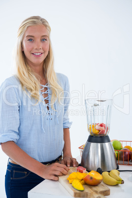 Portrait of smiling woman standing near kitchen worktop