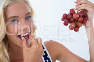 Portrait of beautiful woman eating red grapes