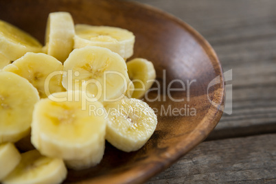 Slices of banana in plate on wooden table