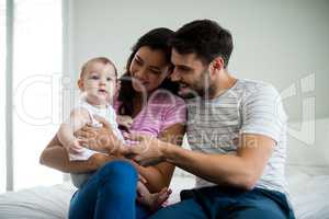 Couple playing with their baby girl on bed