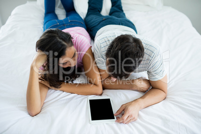 Couple using digital tablet in the bedroom