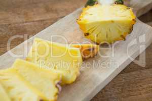 Slices and halved pineapple kept on chopping board