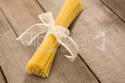 Bundle of raw spaghetti tied with white ribbon