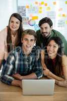 Smiling creative business team discussing over laptop