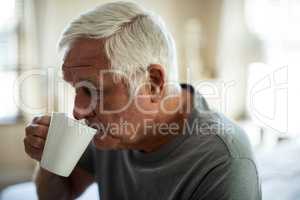 Worried senior man having black coffee in the bedroom