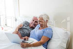 Senior couple using laptop in the bedroom