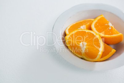 Slices of oranges in bowl on white background