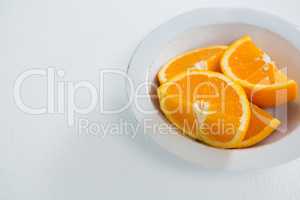 Slices of oranges in bowl on white background