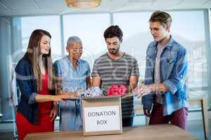 Creative business team sorting clothes in donation box