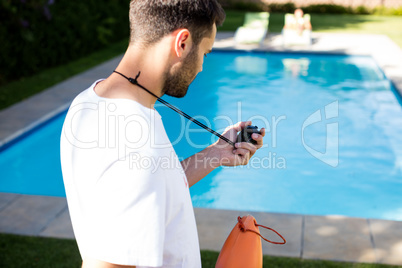 Lifeguard holding stopwatch at poolside