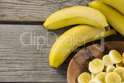 Banana and slices of banana in plate on wooden table
