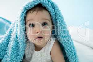Cute baby girl under the blanket on bed