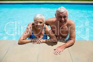 Portrait of senior couple relaxing together in pool