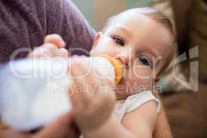 Father feeding milk to baby girl