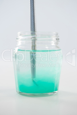 Paintbrush with turquoise paint dipped into water