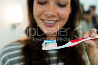 Close-up of happy young woman holding toothbrush with toothpaste