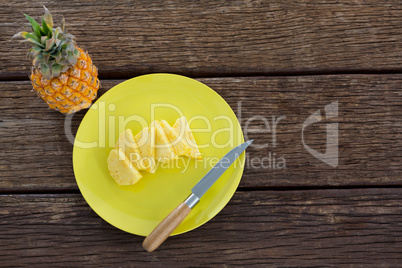 Slices of pineapple in plate on wooden table