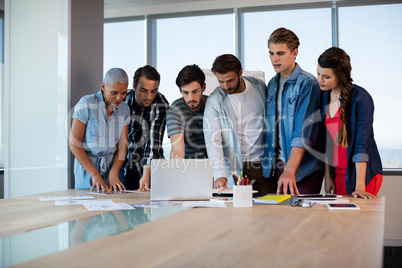 Creative business team looking at presentation in laptop