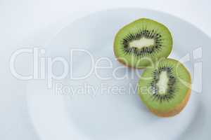 Halved kiwis in plate on white background