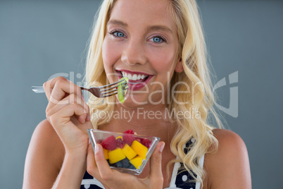 Portrait of woman eating fruit salad in bowl