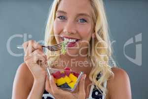 Portrait of woman eating fruit salad in bowl