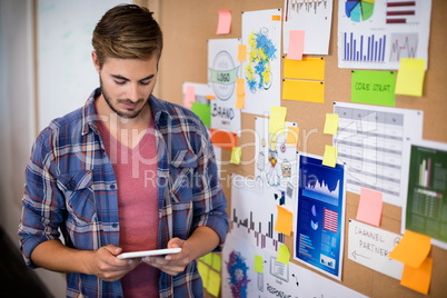 Man using digital tablet next to the board with sticky notes