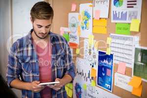 Man using digital tablet next to the board with sticky notes