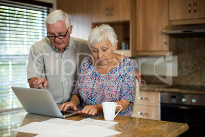 Senior woman using laptop in the kitchen